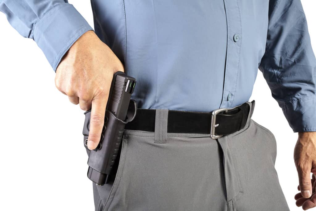 Man holding his hand on a holstered pistol