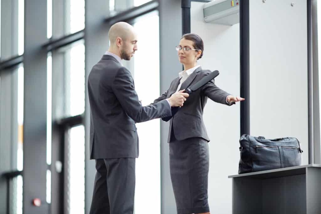 A security guard using a metal detector with customer